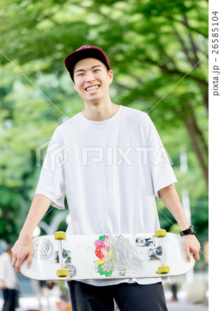 笑顔でスケートボードを手に持つ男性の写真素材