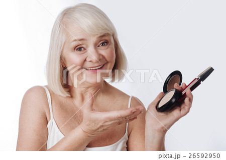 Pleasant retired woman holding face powder and 26592950