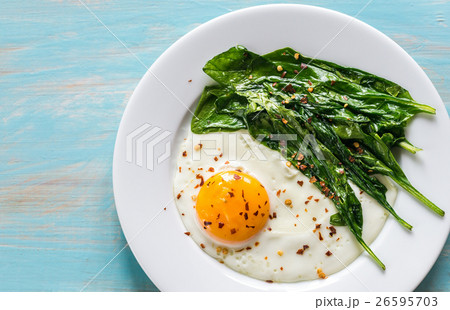 Fried egg with spinach on the wooden table Fried egg with spinach on the wooden table 26595703