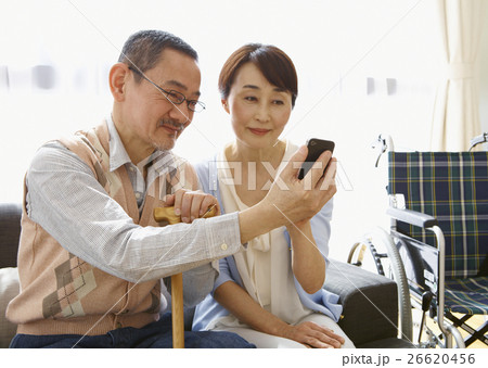 ソファに座ってスマートフォンを操作するシニアの夫婦 26620456