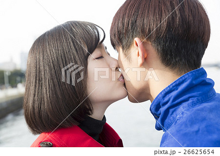 カップル 恋人 男女 キス 口づけ 告白 外 横浜 海背景 トリコロールの写真素材