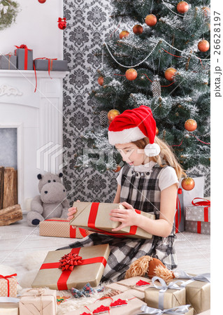 Beautiful girl in santa hat unwrapping christmas 26628197