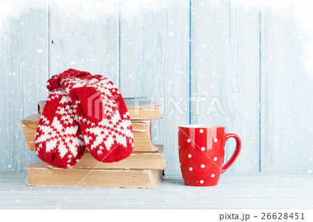 Hot chocolate cup and mittens over books 26628451