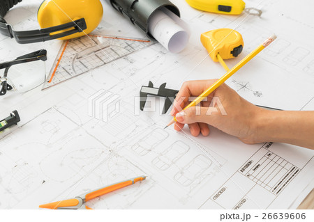 Hand over Construction plans with yellow helmet and drawing tools on blueprints . Hand over Construction plans with yellow helmet and drawing tools on blueprints . 26639606
