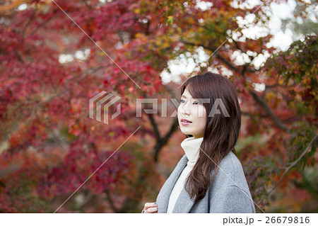 奈良県奈良市の奈良公園の紅葉を背景にしている若い女性 26679816