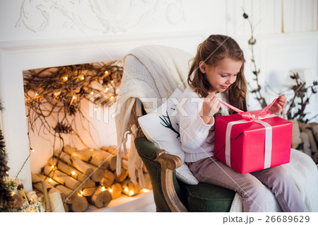 Happy girl opening Christmas gifts by a decorated 26689629