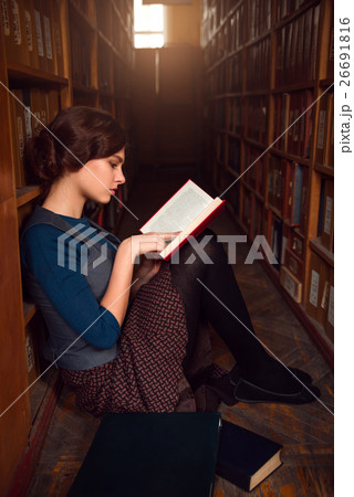 Teenager sitting on a floor of library and read. Teenager sitting on a floor of library and read. 26691816