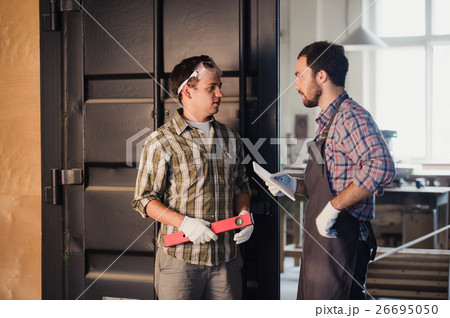 Two carpenters are talking while holding papers Two carpenters are talking while holding papers 26695050