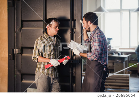Two carpenters are talking while holding papers 26695054