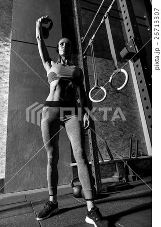 Young slim woman lifting a kettlebell 26713307