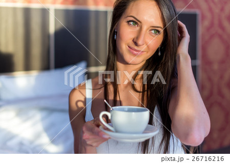 Beautiful woman sitting in bed and drinking coffee Beautiful woman sitting in bed and drinking coffee 26716216