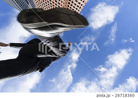 ジャンプ ビジネスマン 真下から見上げる 快晴 青空 ビジネス街 靴の裏底 ボディパーツ の写真素材