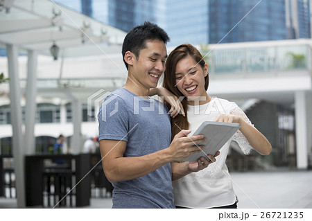Asian man and woman using digital tablet outdoors. 26721235