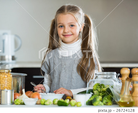 Smiling little girl learning to cook in kitchen Smiling little girl learning to cook in kitchen 26724128