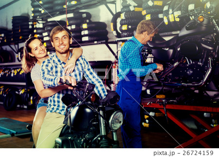 couple sitting on new motorbike in workshop. 26724159