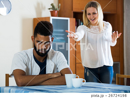 Blonde girl yelling at black boyfriend as quarreling indoors Blonde girl yelling at black boyfriend as quarreling indoors 26724198