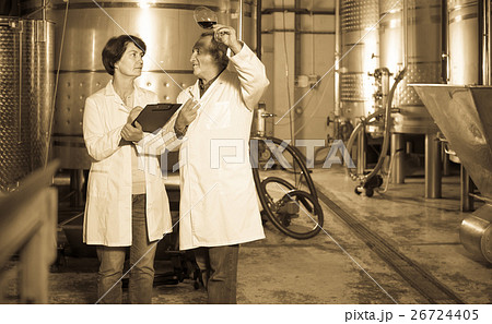 Expert and wine maker estimate quality of red wine in wineglass 26724405