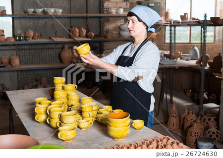 elderly woman with cups at pottery workshop. 26724630