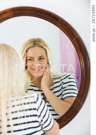 Cute girl watching herself in mirror indoors Cute girl watching herself in mirror indoors 26724995