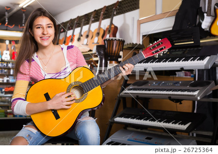 Adult female customer trying to play new guitar 26725364
