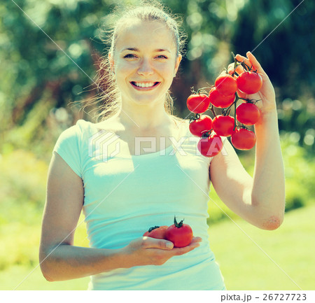 Young woman with tomato in garden Young woman with tomato in garden 26727723