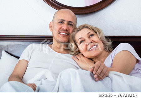 Mature loving couple lounging in bed after awaking cuddling 26728217