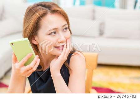 部屋でスマホを見る女性 26745782