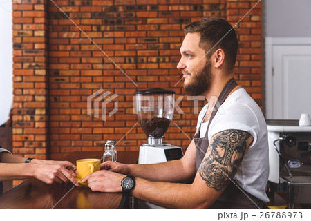Cheerful barista giving mug of coffee to customer Cheerful barista giving mug of coffee to customer 26788973