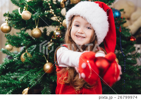 Cheerful girl in red hat hold a tree decoration Cheerful girl in red hat hold a tree decoration 26799974