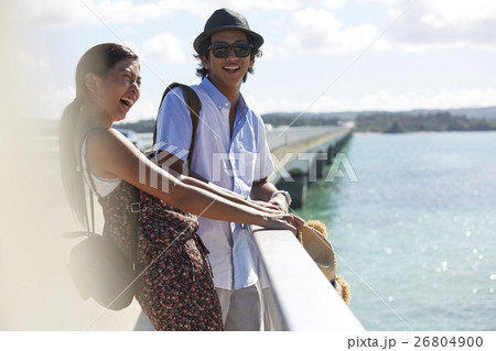 沖縄を旅するカップル　離島へ続く橋 26804900