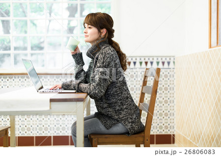 ダイニングテーブルでノートパソコンを使ってネットを楽しむ若い女性 ダイニングテーブルでノートパソコンを使ってネットを楽しむ若い女性 26806083