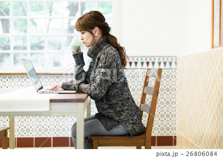 ダイニングテーブルでノートパソコンを使ってネットを楽しむ若い女性 ダイニングテーブルでノートパソコンを使ってネットを楽しむ若い女性 26806084
