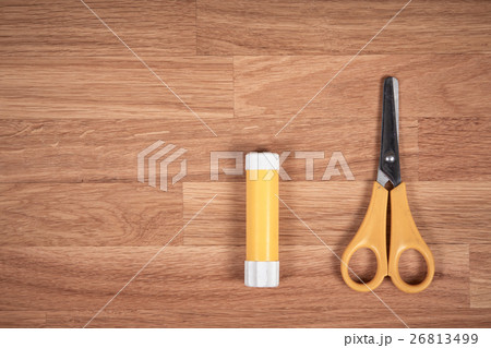 Glue and scissors on a wooden oak table 26813499
