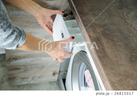 Women's hands holding a container of detergent. 26815017