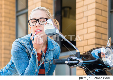 Girl uses rearview mirror of scooter  26823506