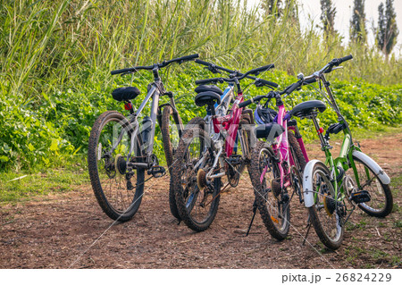 Several bicycles parked on a dirt road Several bicycles parked on a dirt road 26824229