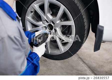 car mechanic screwing or unscrewing  wheel of 26830557