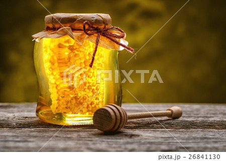 jar of honey with honeycomb with wooden dipper on  26841130