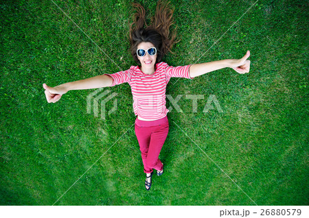 beautiful young woman lying on the green grass in 26880579