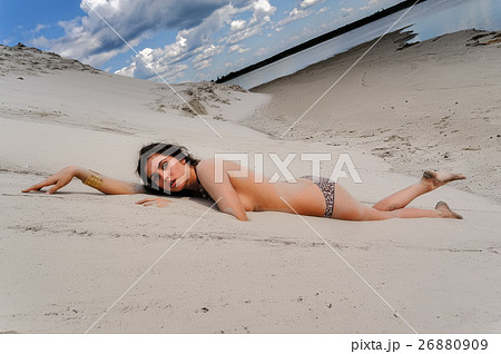 Attractive topless woman relaxes on sand 26880909