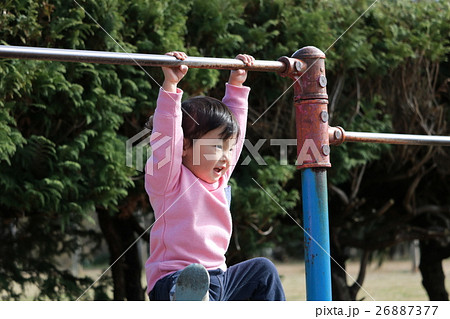 鉄棒にぶら下がる子供の写真素材