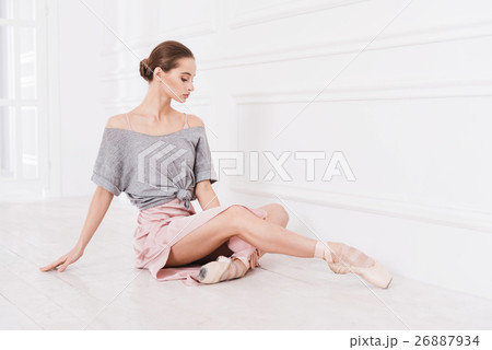 Serious young ballerina sitting on the floor Serious young ballerina sitting on the floor 26887934