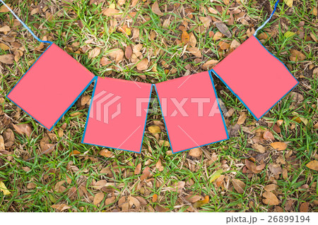 blank red paper sign on green grass background. co 26899194