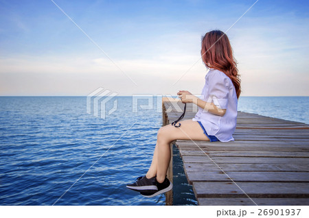 Girl sitting alone on a the wooden bridge. 26901937