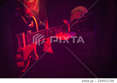 Guitar player on a stage with red light 26903198