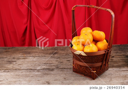 Basket of mandarin oranges on wooden surface 26940354