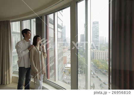 Young couple looking out large windows at view Young couple looking out large windows at view 26956810