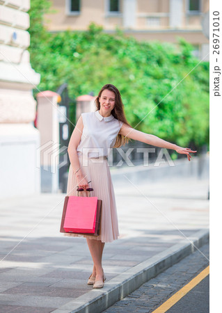 Young happy girl with shopping bags catch a taxi 26971010