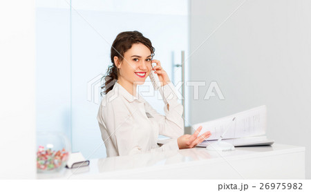 friendly woman behind reception desk administrator 26975982