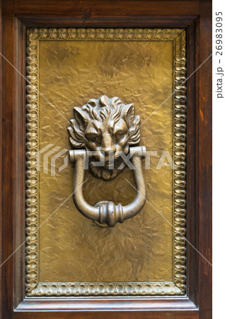 lion head knocker on brass panel of wooden door 26983095